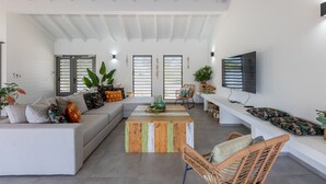 Un salón amplio con un sofá grande, una mesa de centro y un televisor instalado en la pared.