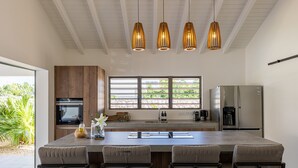 Una cocina moderna con una isla central, electrodomésticos integrados e iluminación colgante.