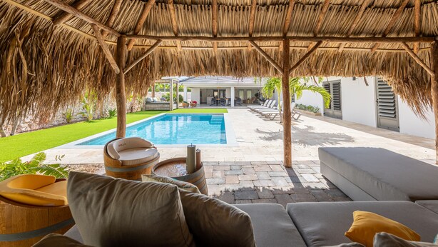Un espacio exterior cubierto con piscina, asientos y vistas a la casa.