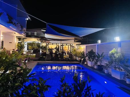 Una piscina al aire libre, sombrillas, sillones reclinables de piscina