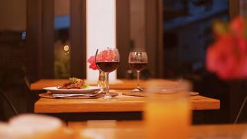 Una mesa de comedor con dos copas de vino y un plato de comida, frente a una ventana con vistas al cielo nocturno.