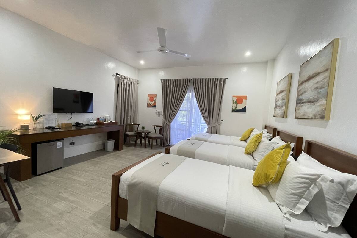 Una habitación de hotel con dos camas, un escritorio, televisión y un pequeño rincón de descanso.