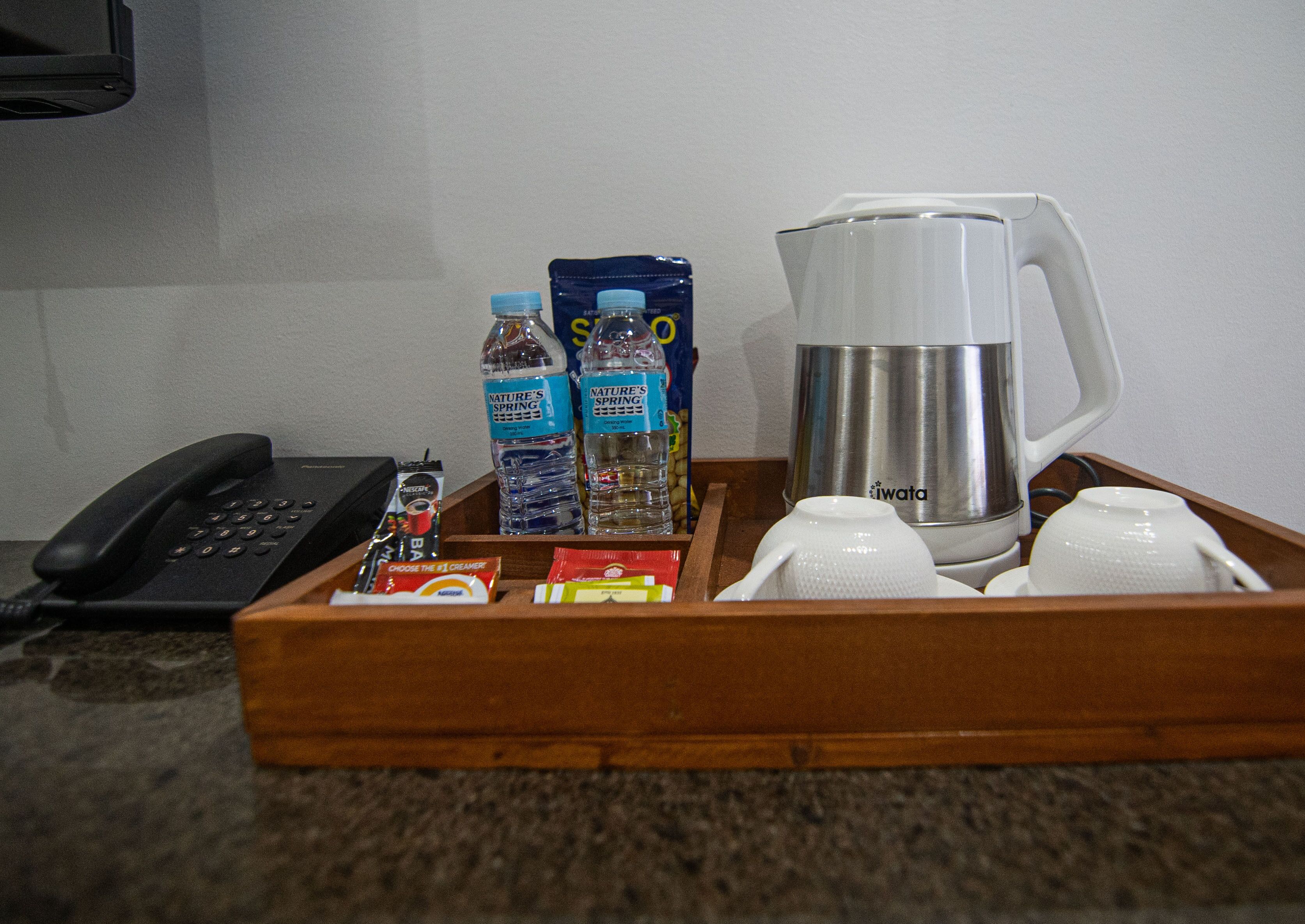 Un plateau avec une machine à café, deux bouteilles d’eau, un téléphone et quelques en-cas.
