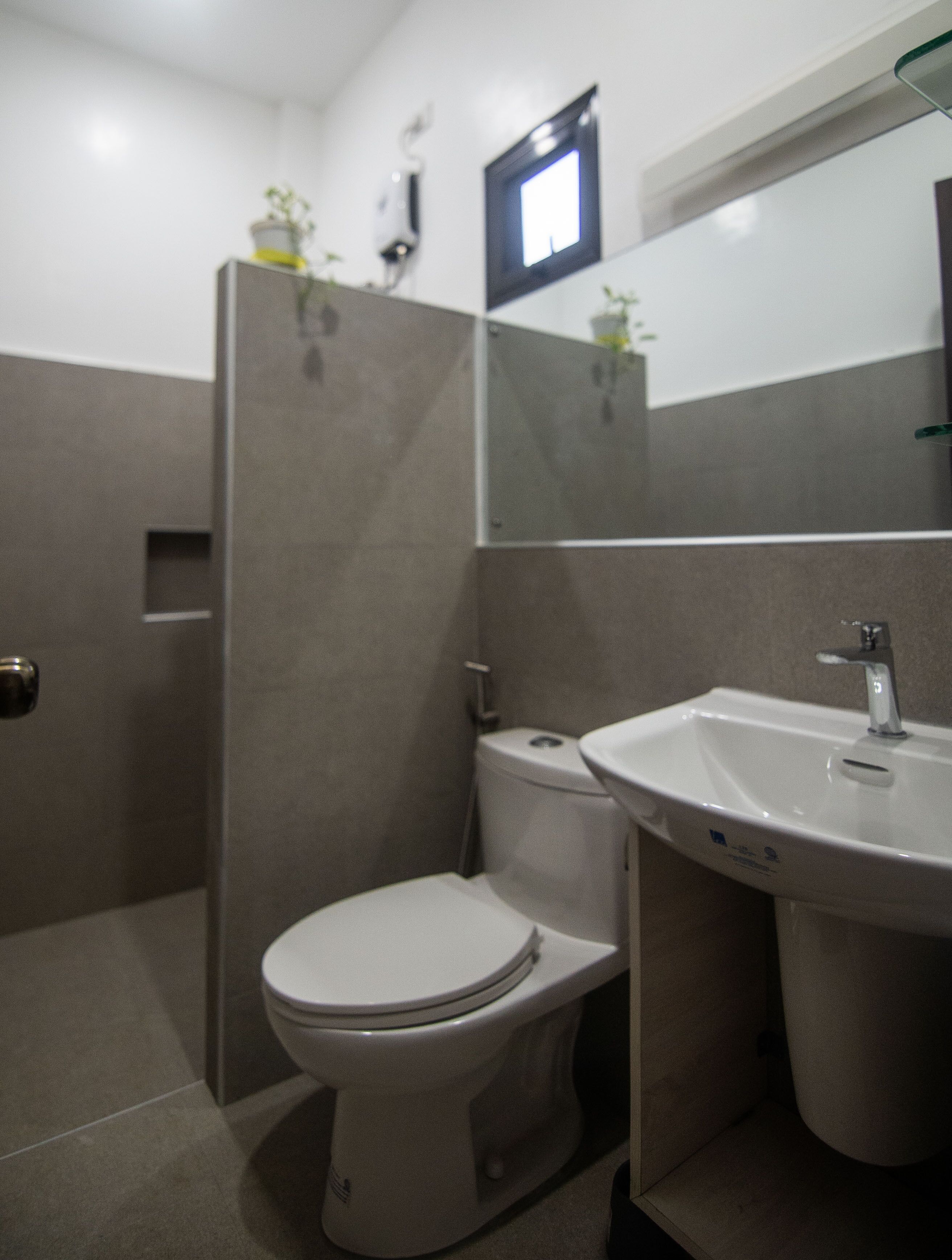 A modern bathroom with a toilet, sink, and mirror.