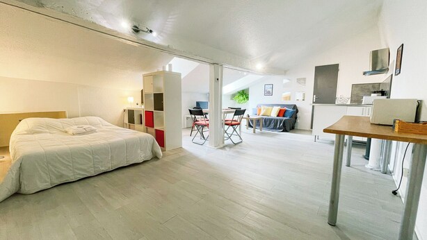 A spacious room with a bed, a desk, and a sofa. There is a kitchenette area with a microwave and a sink. - #EH  |  Le Rousseau 🤍 (Grenoble)