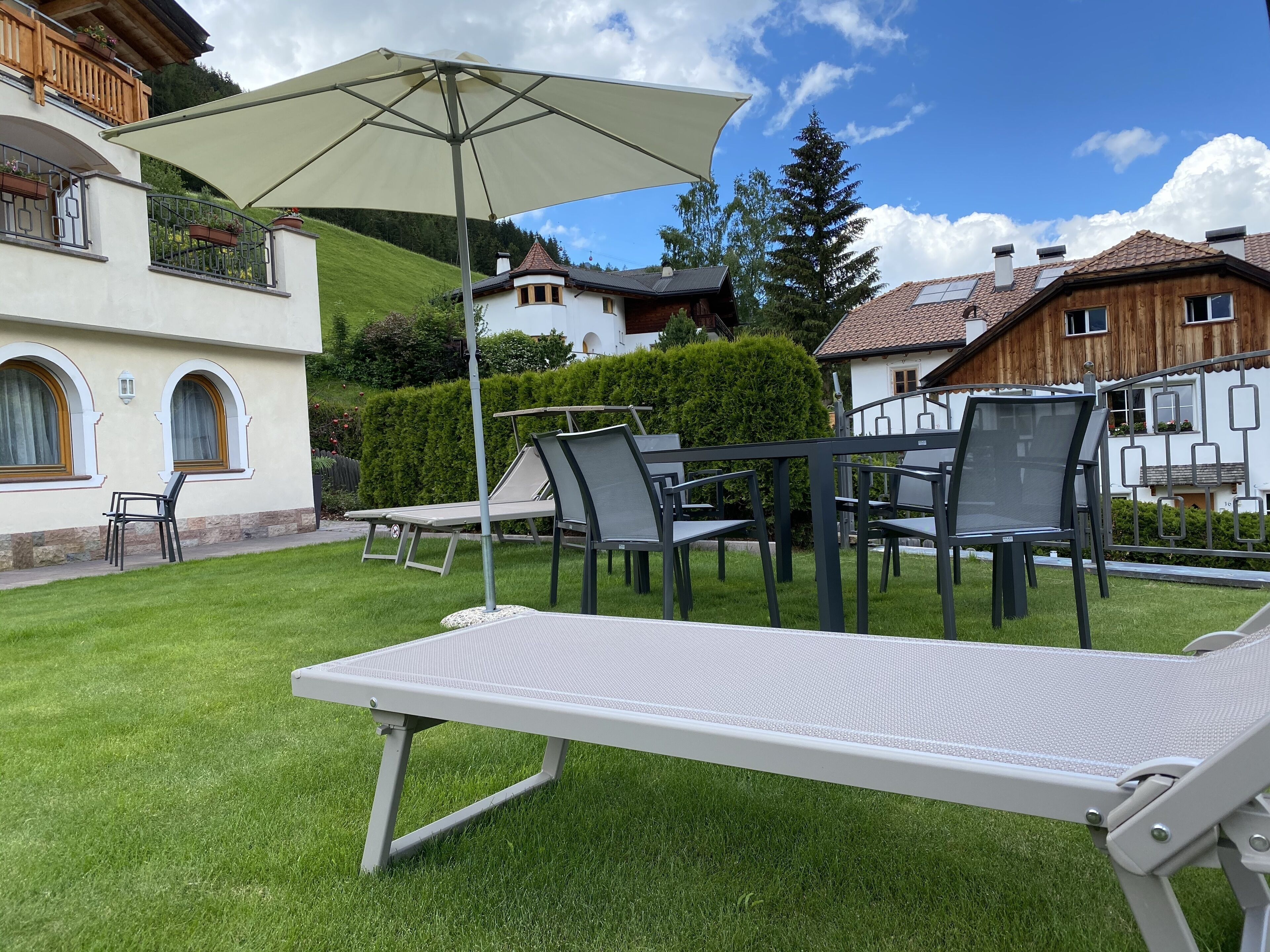 A patio area with a lounge chair, a table, and a large umbrella.