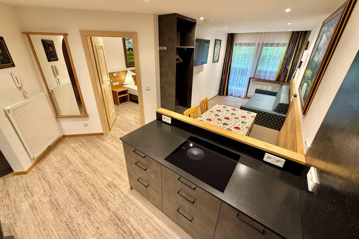 A compact kitchen with a central island, a dining area with a table and chairs, and a small seating area with a sofa.