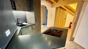 A modern kitchen with a black countertop, wooden cabinetry, and a visible sink. - Residence Palmai (Castelrotto)