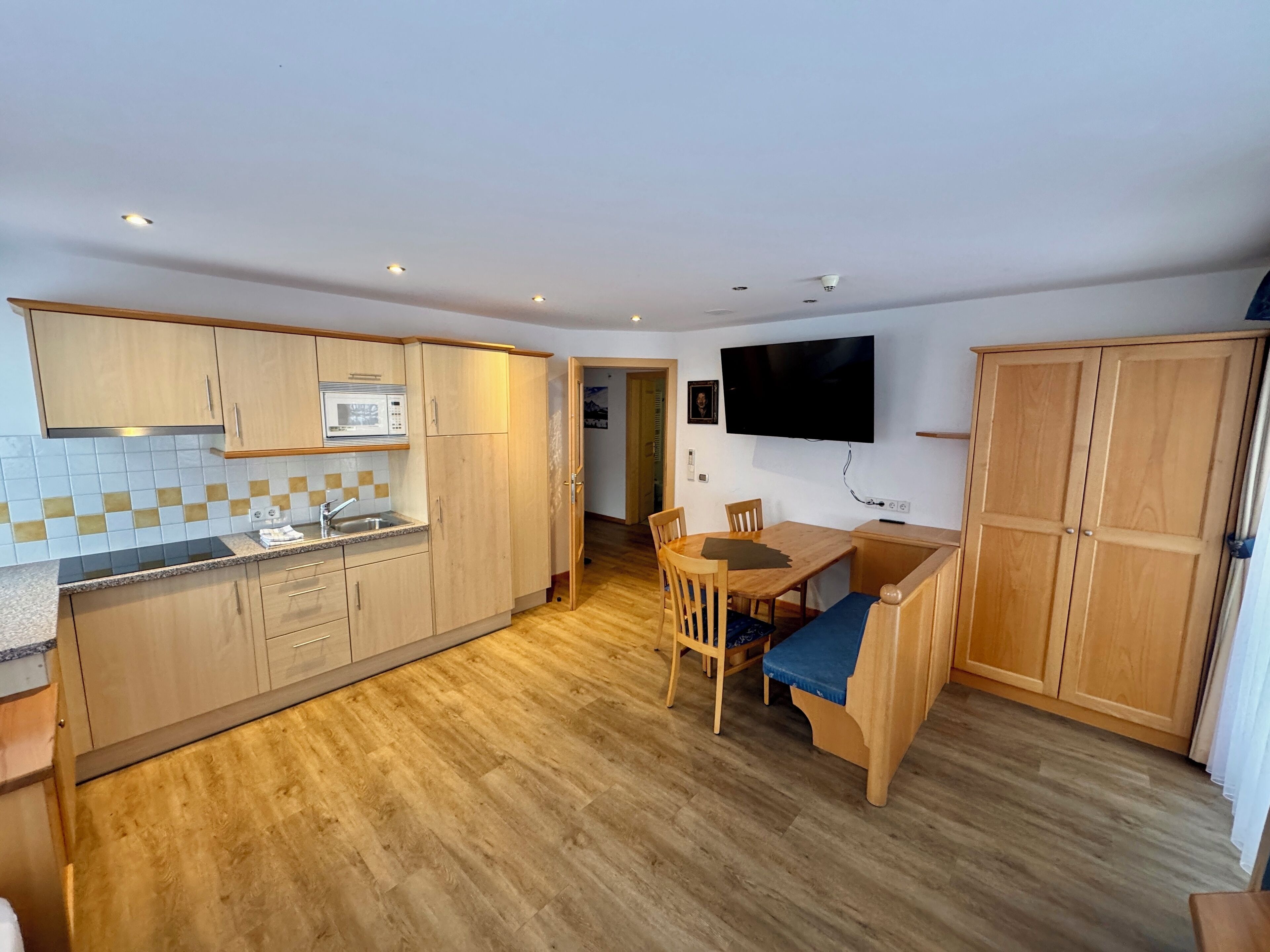Una cocina compacta con armarios de madera, un microondas y un comedor con mesa y sillas.