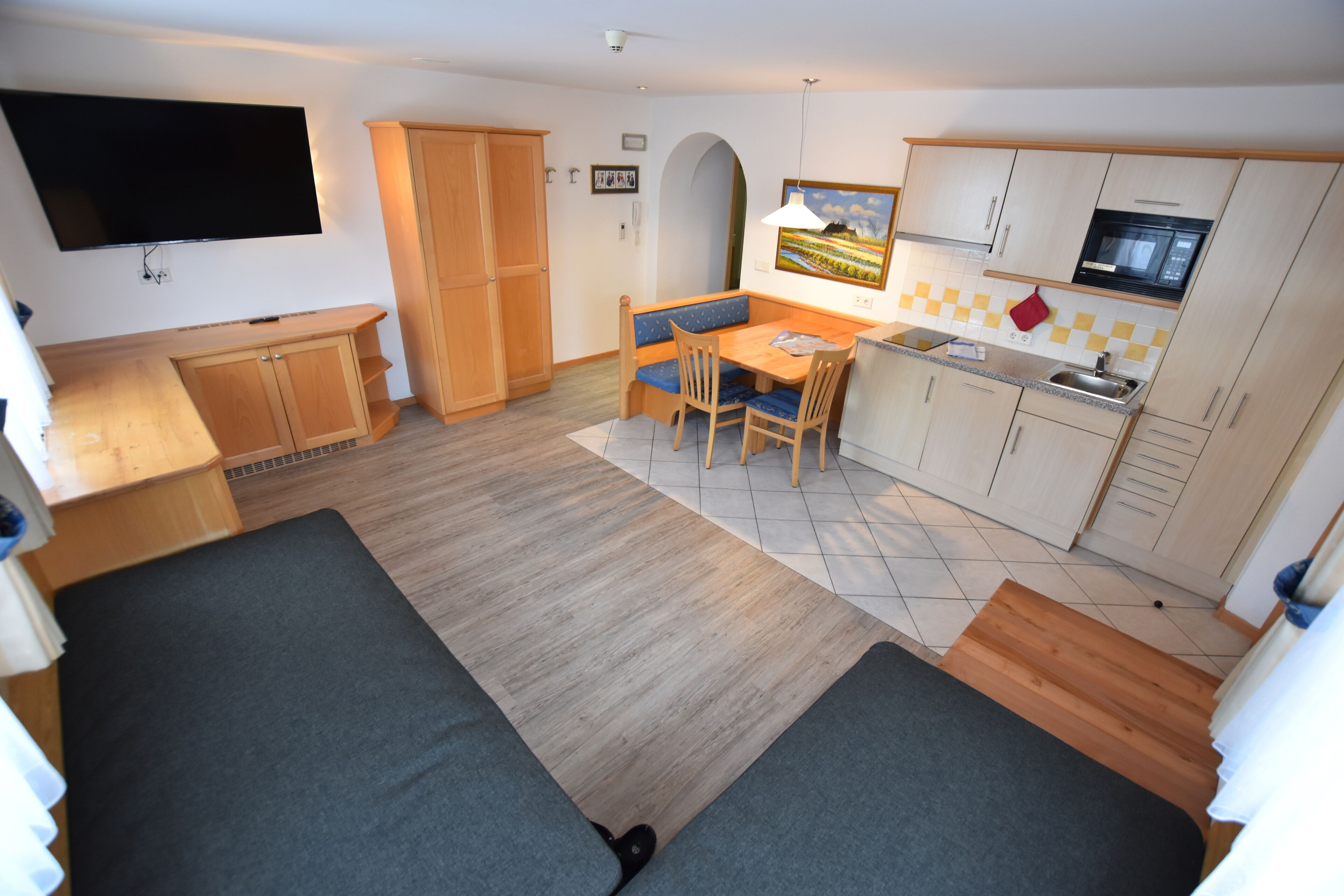Un espacio habitable compacto con sofá, mesa de comedor y kitchenette.