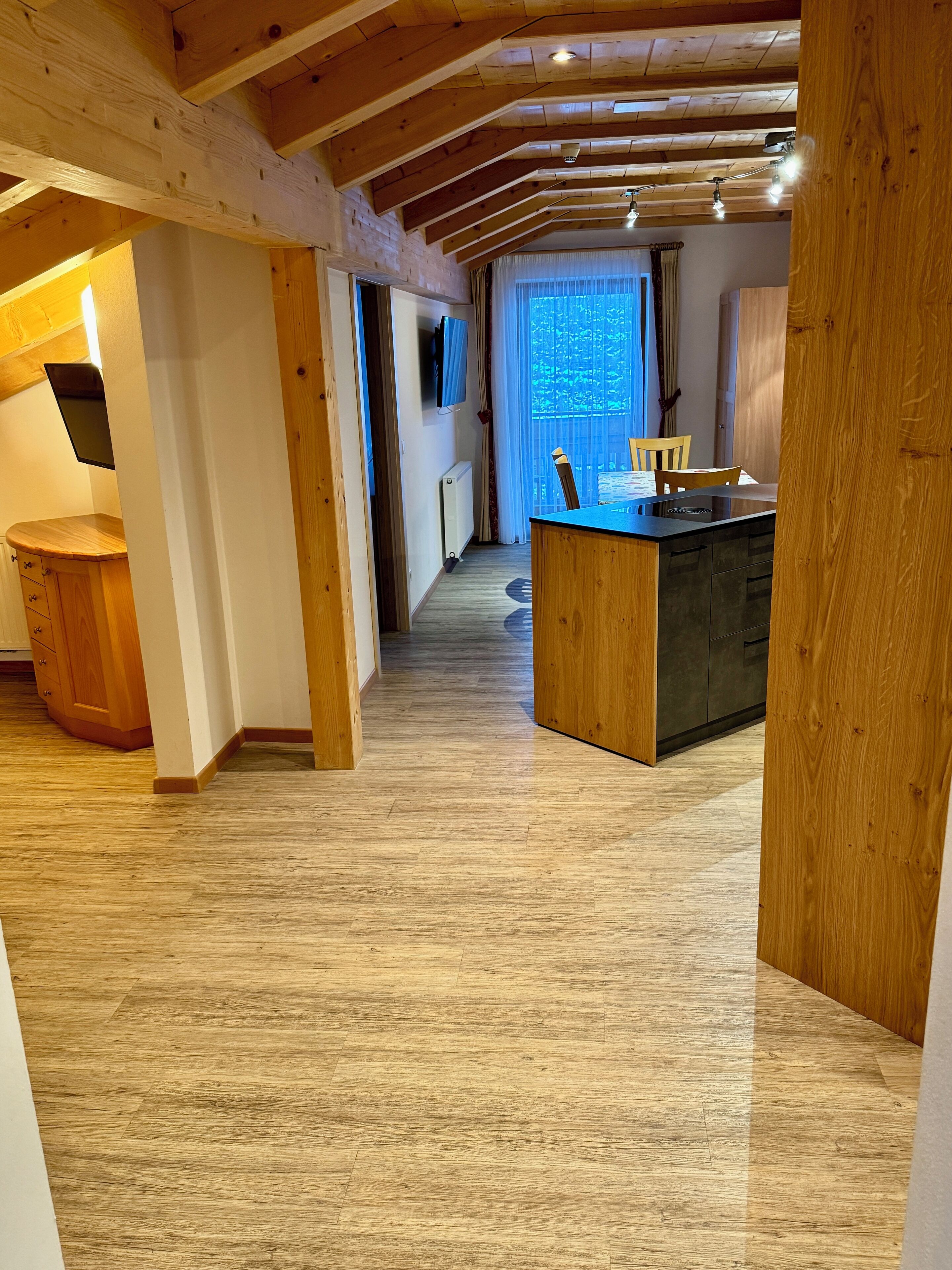 A spacious kitchen with wooden beams, a central island, and a large window providing natural light.