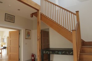 A wooden staircase with a handrail, a fire extinguisher, and a door leading to another room. - White Horses Bantham South Devon (Bantham)