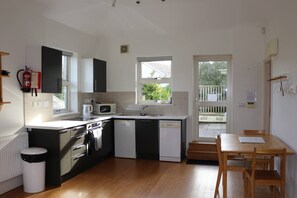 A compact kitchen with a microwave, sink, and dishwasher. There's a window providing natural light and a view of the outside. - White Horses Bantham South Devon (Bantham)