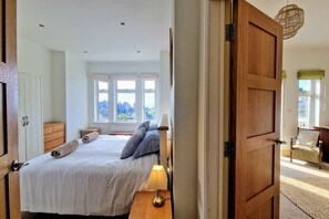 A bedroom with a bed, bedside tables, a lamp, and a view of the outdoors through a window. - White Horses Bantham South Devon (Bantham)