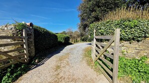 A gravel path leading to a stone wall with a wooden gate. - White Horses Bantham South Devon (Bantham)