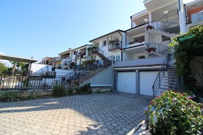 Un immeuble résidentiel doté de nombreux balcons, d’un escalier central et d’un garage.