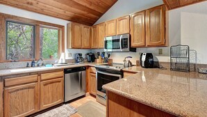 Una cocina con armarios de madera, un microondas de acero inoxidable, una cafetera y un hervidor.