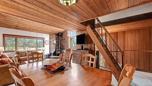 Un comedor amplio con una mesa y sillas de madera, una chimenea y una escalera.