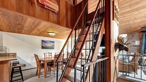 Un interior de madera con una escalera, comedor y chimenea.