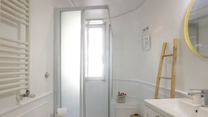 Une petite salle de bain avec une douche, deux lavabos et un miroir.