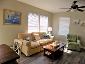 A living room with a sofa, a coffee table, a chair, and a ceiling fan.