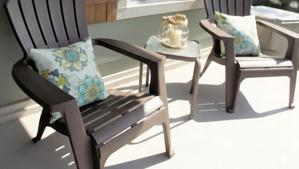 Two wooden Adirondack chairs with floral cushions on a porch.