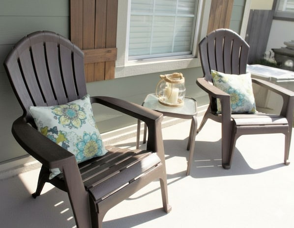 Two wooden Adirondack chairs with floral cushions on a porch.