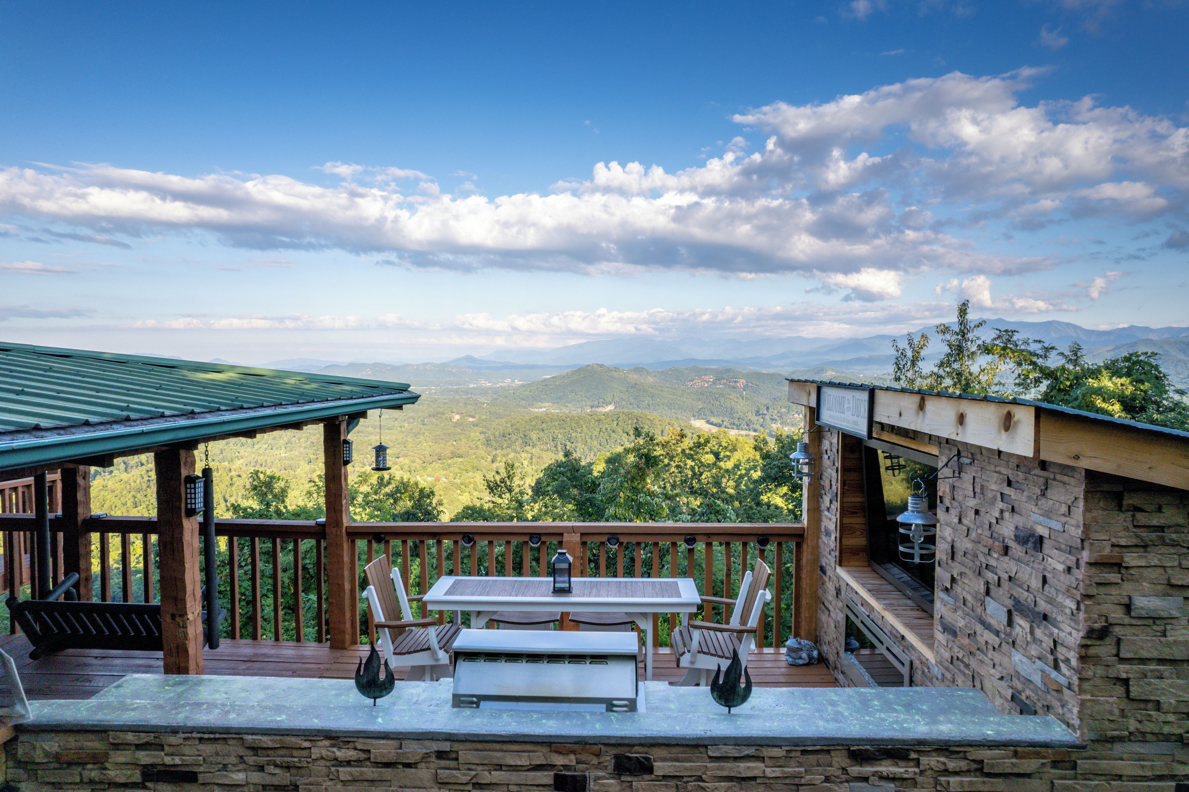 Une terrasse en bois avec une table et des chaises, offrant une vue sur un paysage montagneux.
