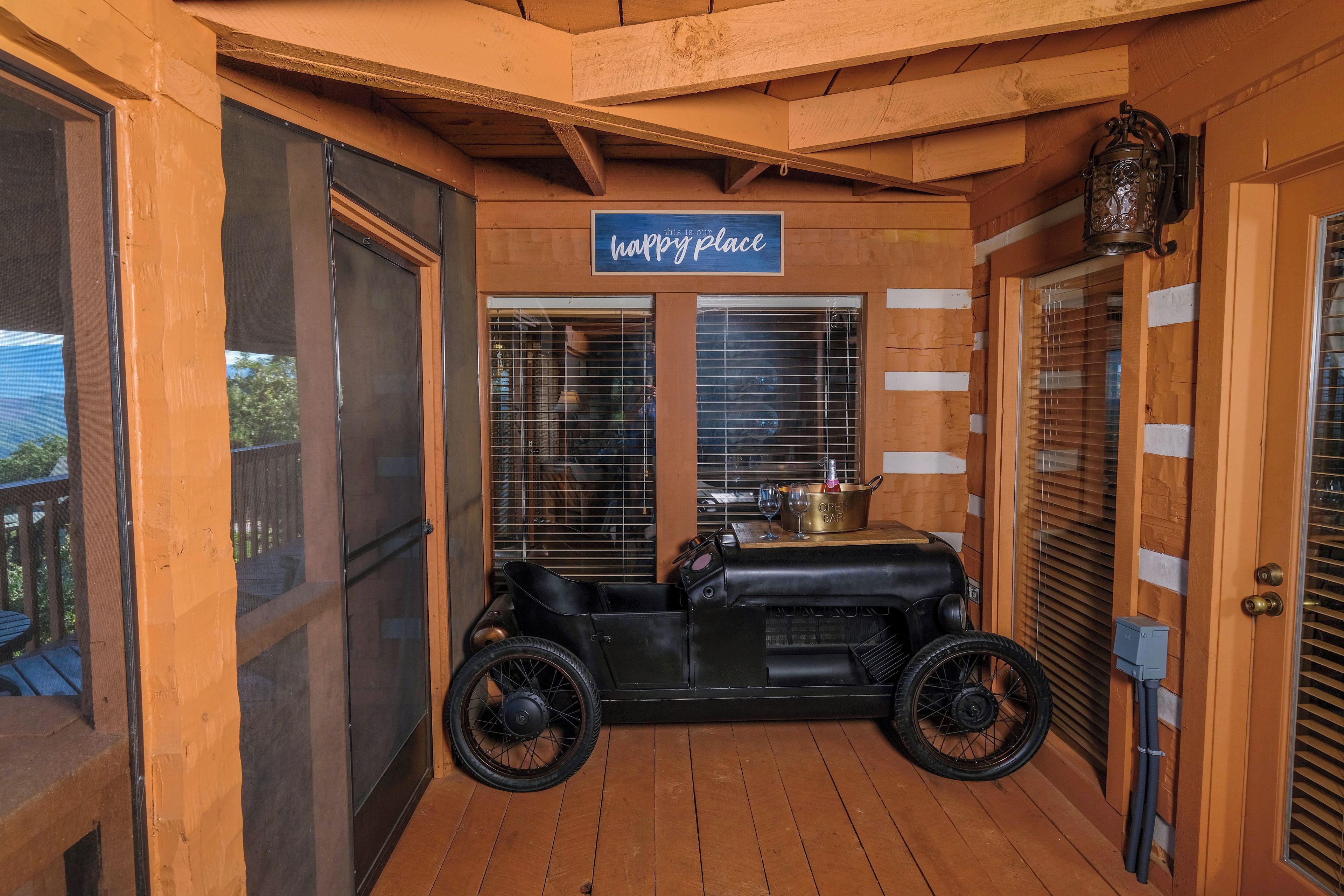 A cozy wooden room with a vintage car, a 'happy place' sign, and a view of the outdoors.