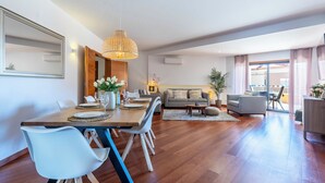 Un salon moderne comprenant un coin repas, un canapé et une grande fenêtre.