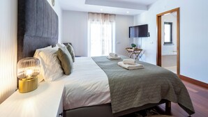 Une chambre à coucher bien rangée, avec un lit, une lampe de chevet et un téléviseur à écran plat fixé au mur.