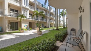 A hotel courtyard with a paved walkway, potted plants, and outdoor seating.