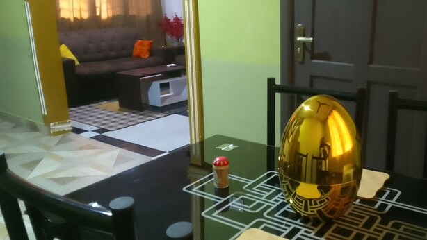 Una mesa de comedor con un cuenco dorado, un objeto pequeño rojo y un alimento envasado.