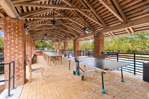 An outdoor patio area with a ping pong table, seating, and a brick wall. - Close to the Clubhouse with Bikes and LSV (Santa Rosa Beach)