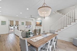 A spacious living area with a wooden dining table, white walls, and a staircase. - Close to the Clubhouse with Bikes and LSV (Santa Rosa Beach)