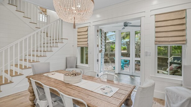 A spacious dining area with a wooden table, white chairs, and a chandelier. - Close to the Clubhouse with Bikes and LSV (Santa Rosa Beach)