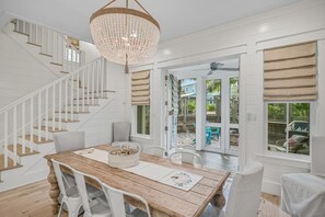 A spacious dining area with a wooden table, white chairs, and a chandelier. - Close to the Clubhouse with Bikes and LSV (Santa Rosa Beach)