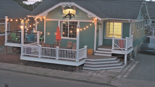 Ein Haus mit Veranda, Sitzgelegenheiten im Freien und Lichterketten.