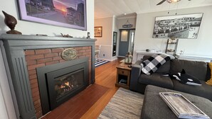 Ein Wohnzimmer mit Kamin, einer Couch, einem Couchtisch und einem Deckenventilator.