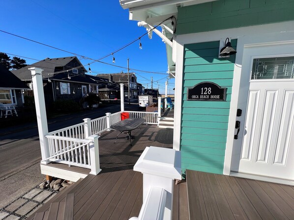 Welcome to 128 Orca Beach House, where a charming porch invites you to relax with a table and chairs.