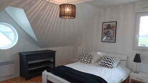 Een slaapkamer met een bed, een bureau, een stoel, een raam en een plafondlamp.