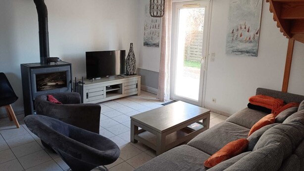 Een woonkamer met een bank, een televisie, een open haard en een schuifpui naar een buitenruimte.