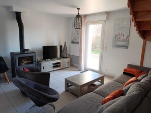 A living room with a sofa, a television, a fireplace, and a sliding glass door leading to an outdoor area.
