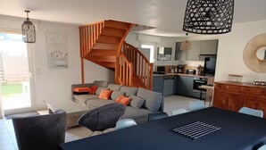 Een moderne woonkamer met een trap, een eethoek en een keuken.