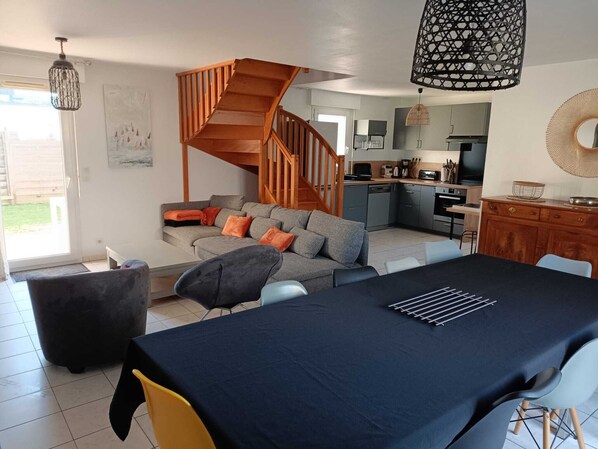 A modern living room with a staircase, a dining area, and a kitchen.