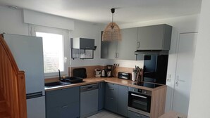 Een moderne keuken met grijze kastjes, een zwarte kookplaat, een inbouwoven en een houten aanrecht.