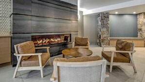 Un salon moderne avec un mur d’accent en pierre, une cheminée et des sièges confortables.