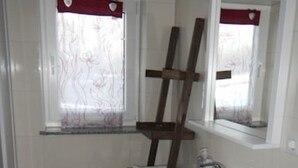 A bathroom with a white sink, a wooden ladder leaning against the wall, a small stool, and a window with a floral curtain. - Seebrise house complete, FH Seebrise (Storkow (Mark))