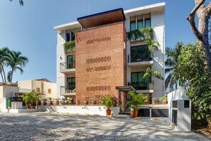 A modern building with a brick facade, multiple balconies, and potted plants.