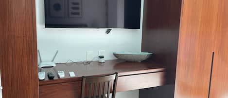 Een kleine kantoorruimte met een bureau, stoel en een grote spiegel erboven.